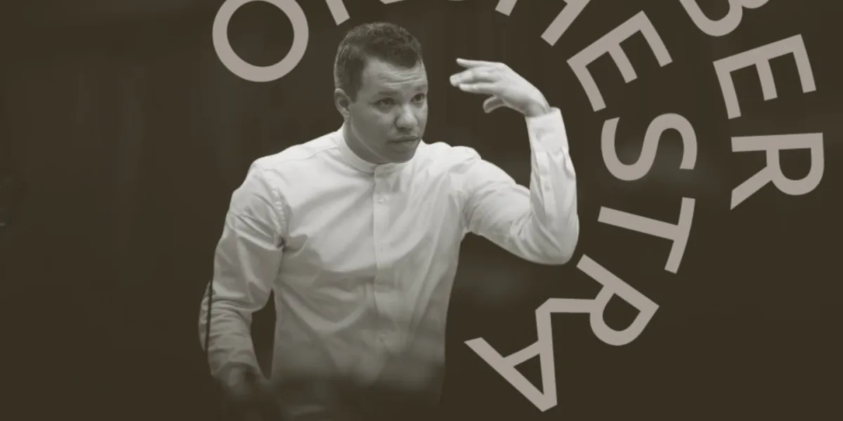 Ryan Bancroft conducts against a dark backdrop in a white shirt